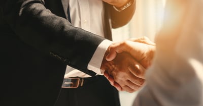 A person in a business suit shaking hands with a colleague