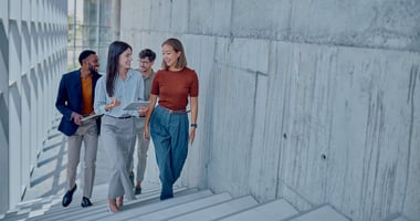 A group of employees walking up the stairs while chatting in a concrete office building