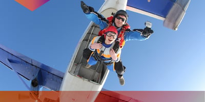 2 friends cheering while skydiving from a plane