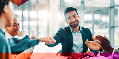 Coworkers fist-bumping in a brightly lit office