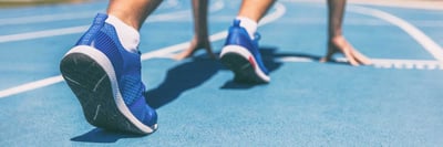Sprinter waiting for start of race on running tracks at outdoor stadium. Sport and fitness runner man athlete on blue run track with running shoes.