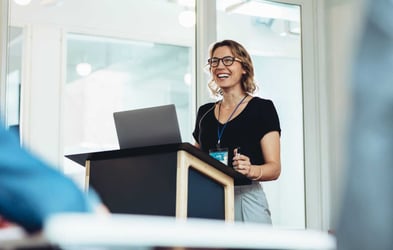 Businesswoman standing at podium with laptop giving a speech. Overcoming presentation anxiety