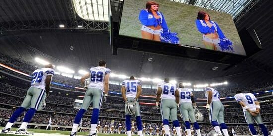 Dallas Cowboys players stand during the National Anthem before their game against the Tennessee Titans pre-season game at Cowboys Stadium in Arlington