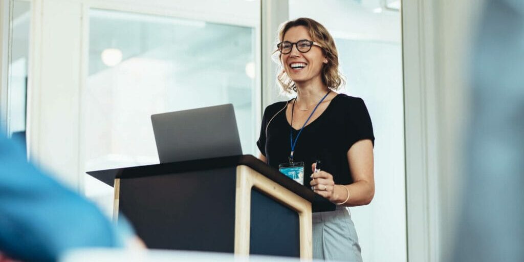 Businesswoman standing at podium with laptop giving a speech. Overcoming presentation anxiety