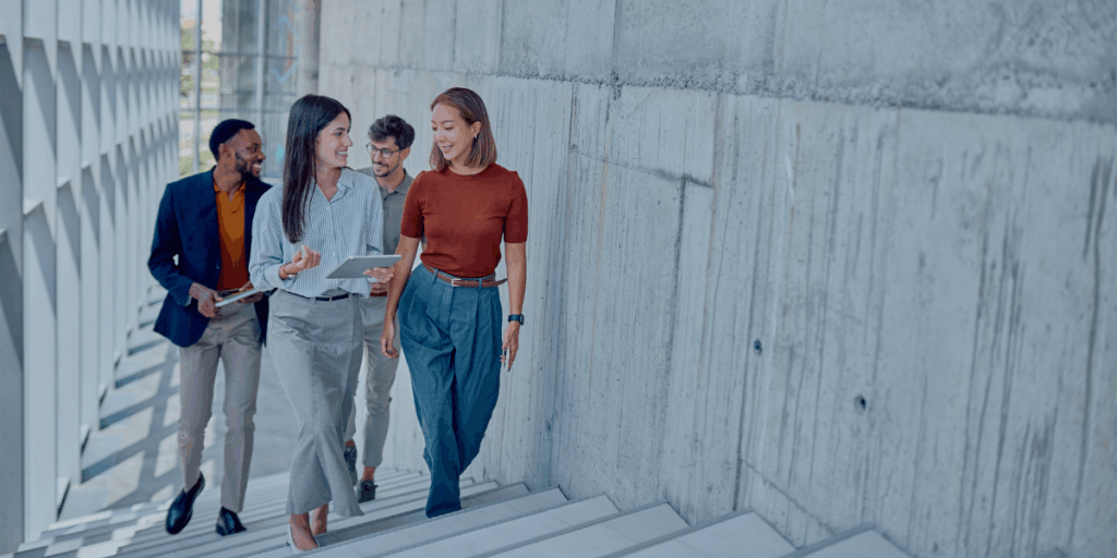 A group of employees walking up the stairs while chatting in a concrete office building